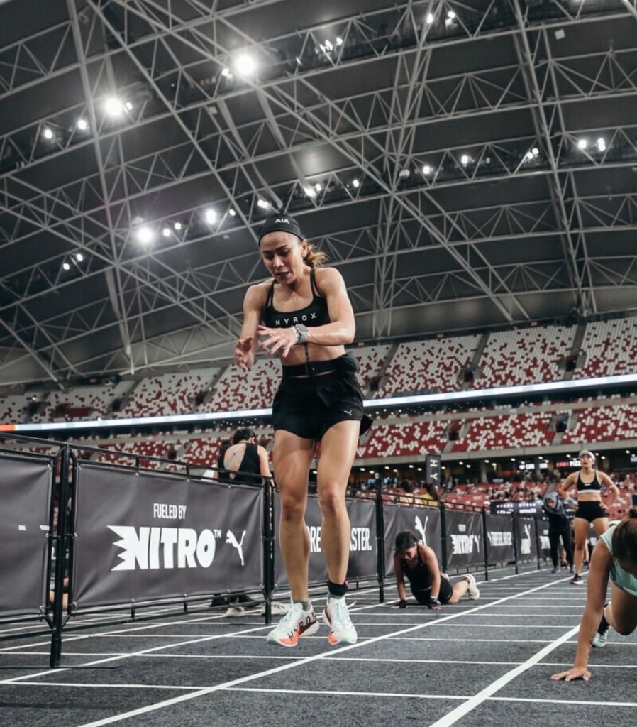 Dina mid broad jump between burpee reps in the arena