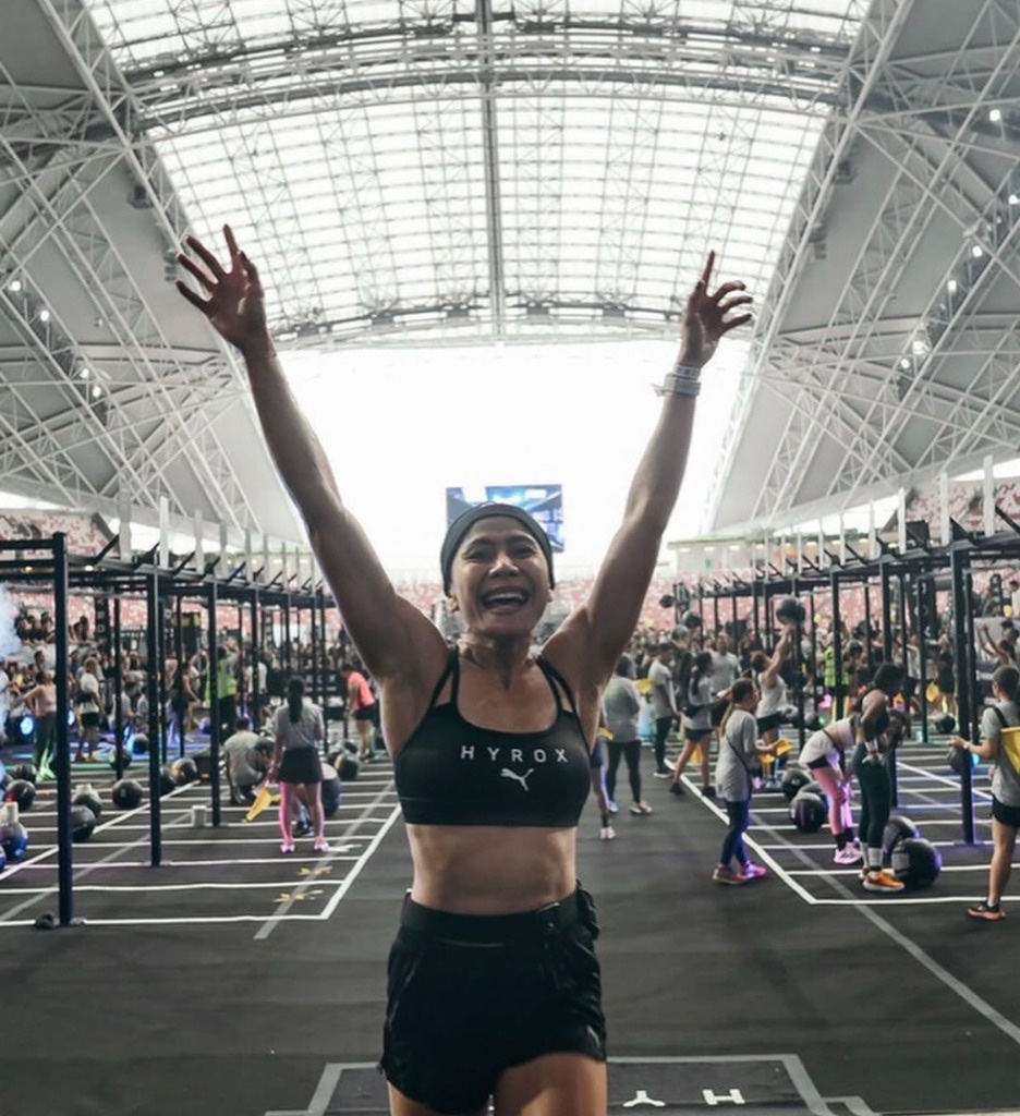 Dina with both arms raised in celebration at the finish line